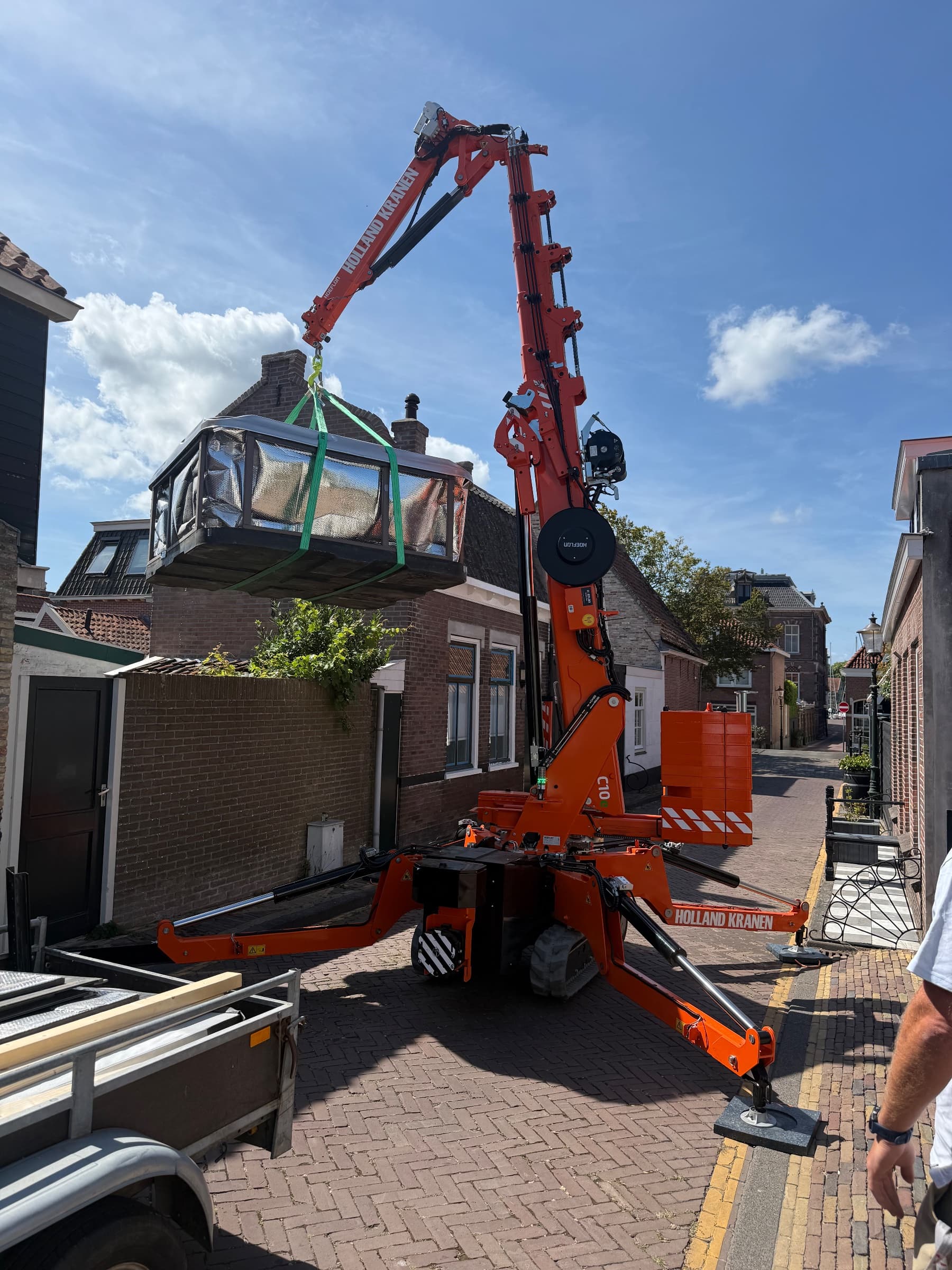 Hoeflon C10 hijst een jacuzzi over een woning in een smalle straat in Medemblik