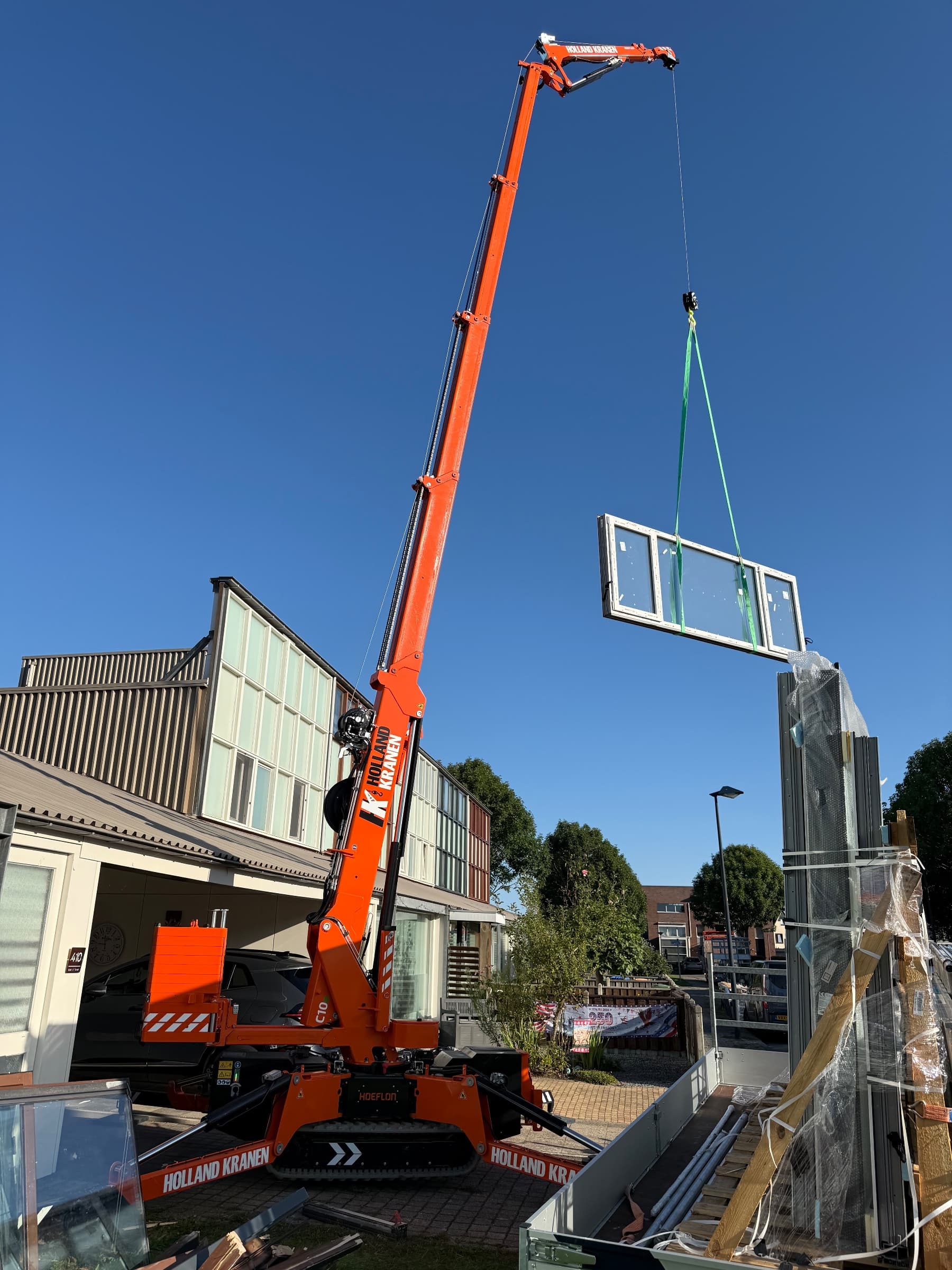 Hoeflon C10 hijst een kozijn aan de lier bij een woning in Lelystad