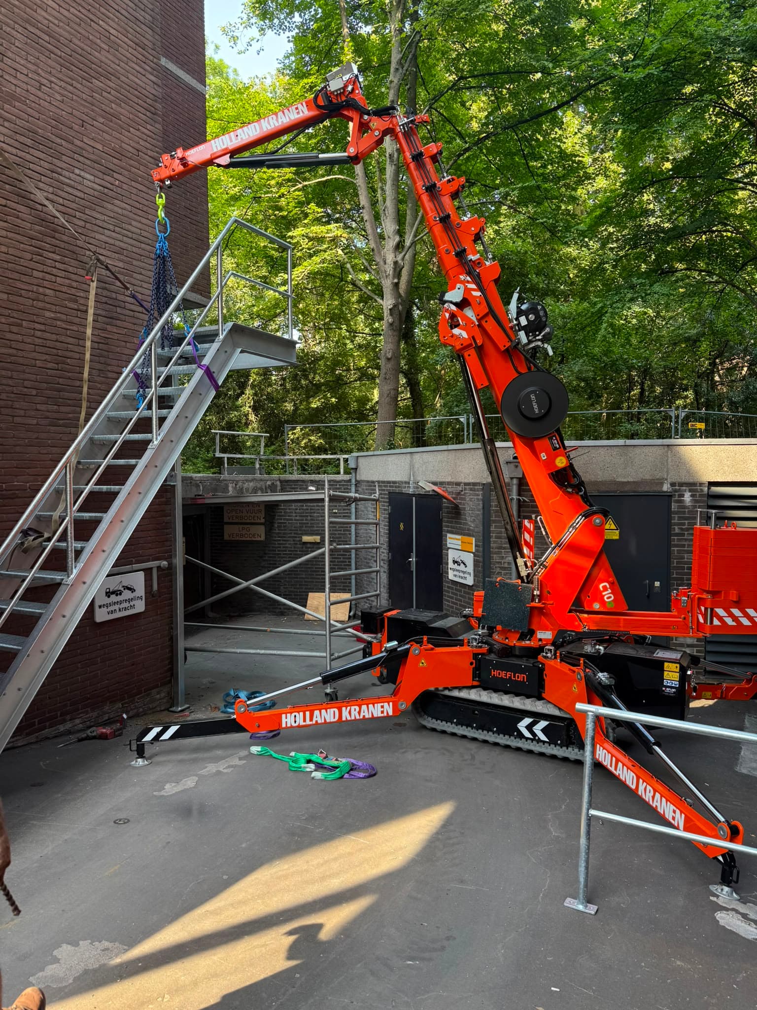 Hoeflon C10 minikraan plaatst een stalen buitentrap